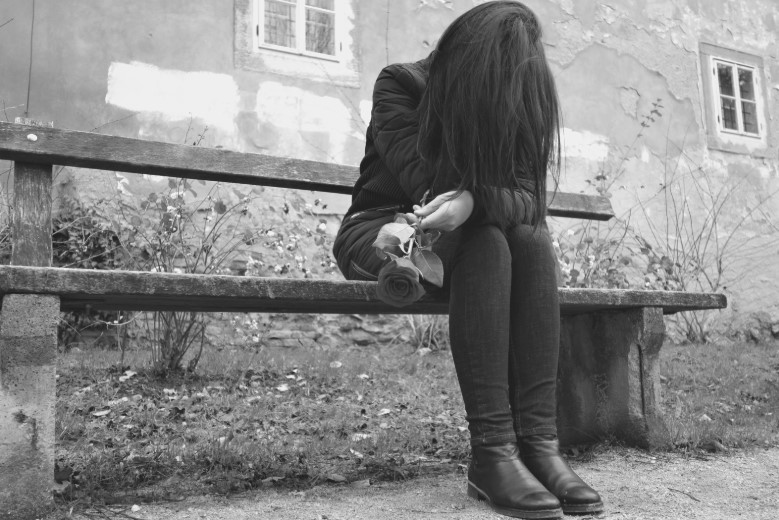 crying woman sitting along on a bench after a funeral
